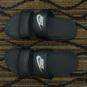 Women’s Nike Benassi Duo ultra slide sandals, in black with white writing.